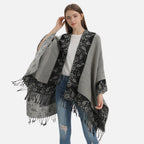 Cape poncho femme grise avec motifs floraux noirs et franges, portée de face