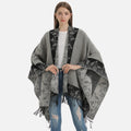 Cape poncho femme grise motifs floraux noirs avec franges, portée de face sur jeans
