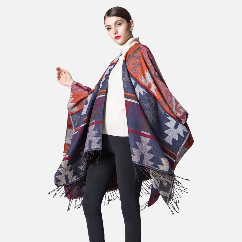 Femme portant cape poncho péruvienne orange bleu avec franges, col roulé blanc, pantalon noir