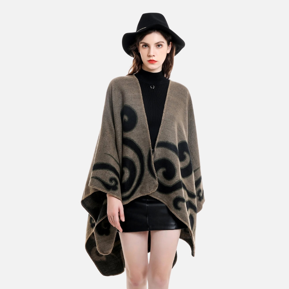 Femme portant cape poncho réversible beige et noir avec motifs arabesques, chapeau noir, vue de face