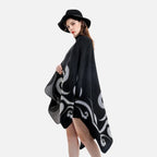Femme portant cape poncho noire réversible avec motifs arabesques gris, vue de dos, chapeau noir