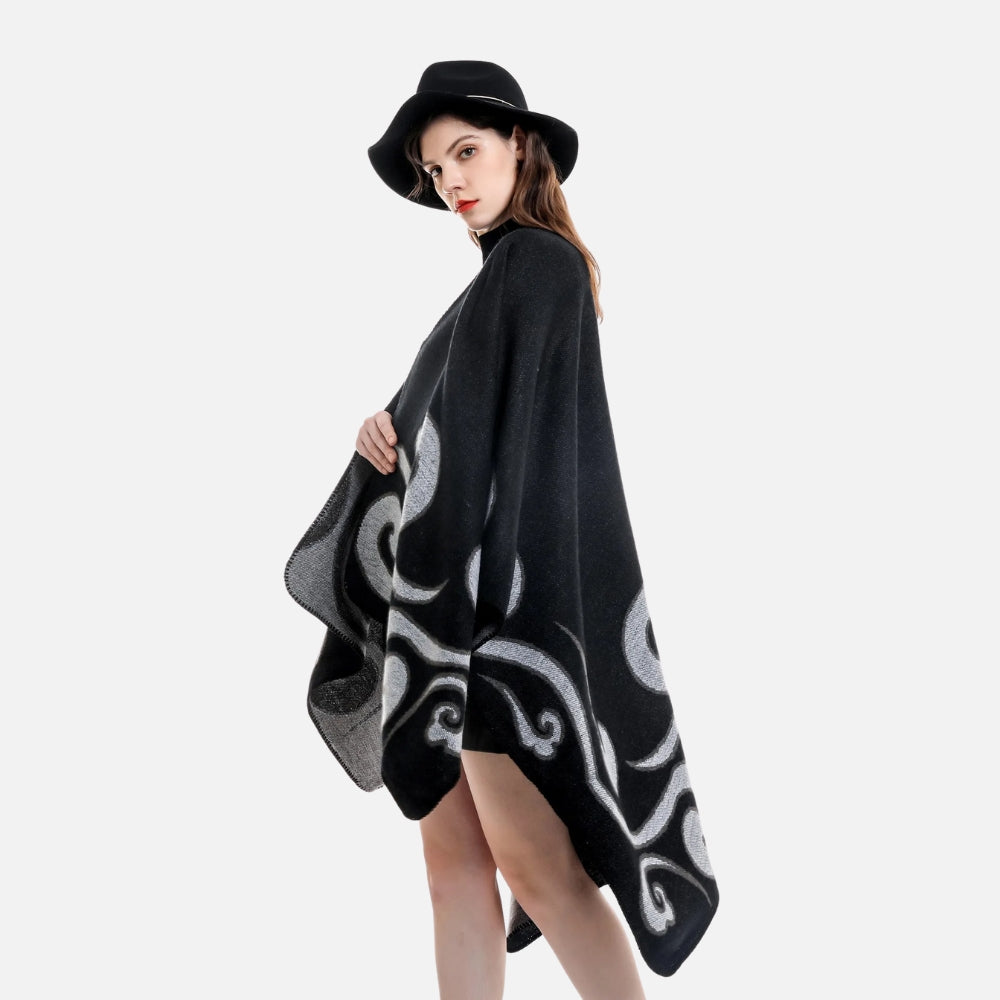 Femme portant cape poncho noire réversible avec motifs arabesques gris, vue de dos, chapeau noir