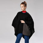Femme portant une cape poncho réversible noire et grise avec col rouge bleu marine
