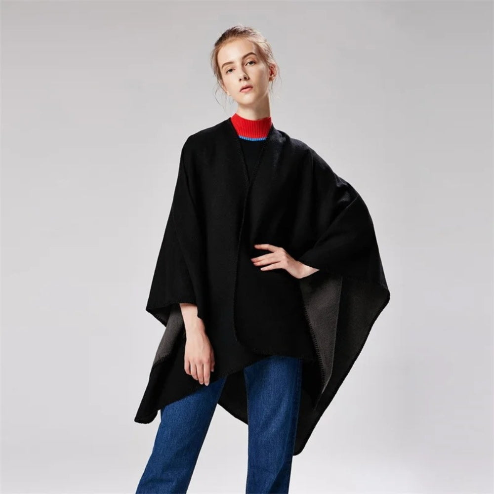 Femme portant une cape poncho réversible noire et gris avec col roulé multicolore rayé