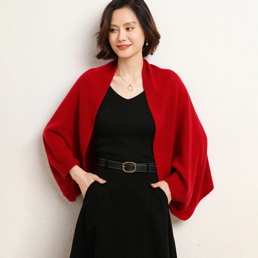 Cape poncho laine rouge femme avec bords côtelés, portée sur top noir et ceinture dorée
