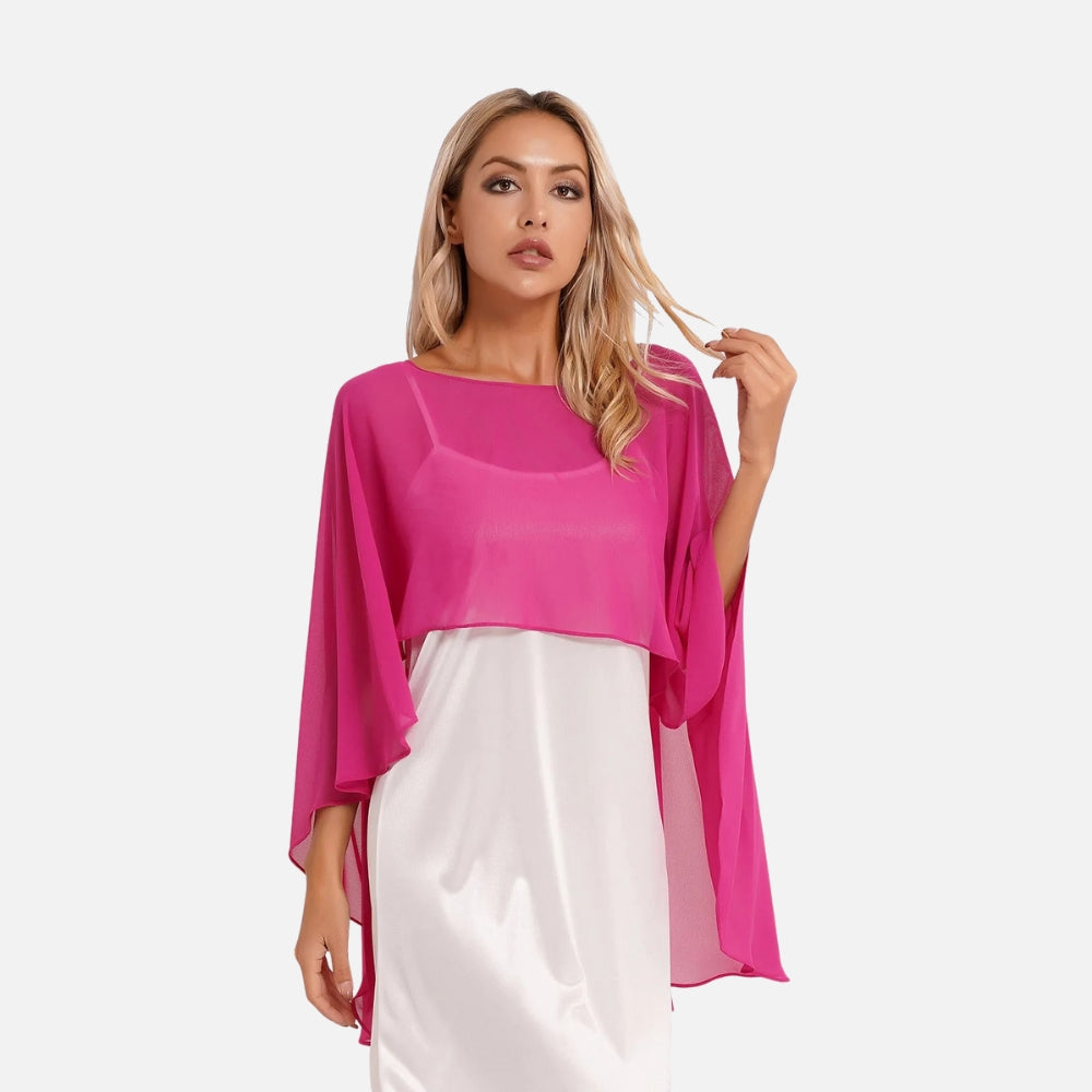 Cape poncho mousseline femme rose fuchsia manches larges, portée de face sur robe blanche