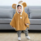 Bébé portant cape poncho polaire beige avec capuche oreilles et pompons blancs