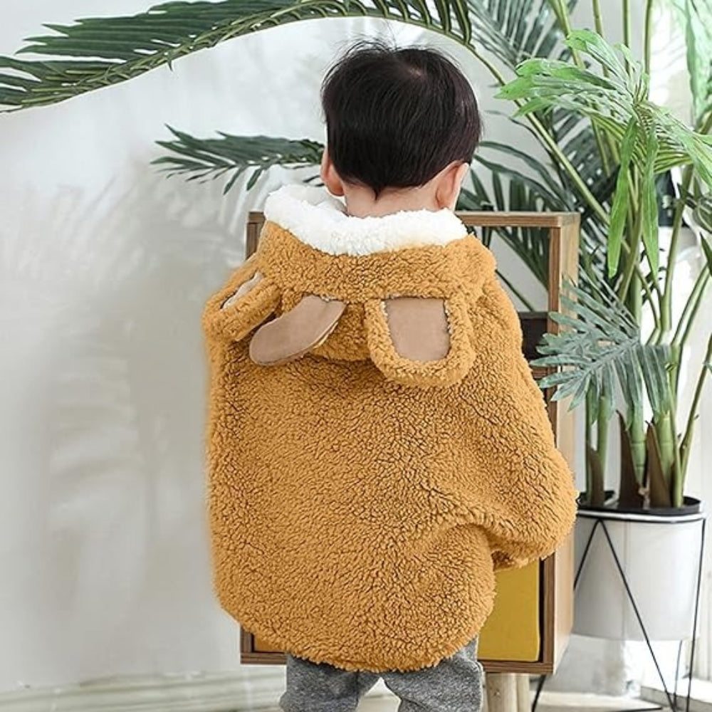 Bébé de dos portant une cape polaire camel avec col blanc et oreilles pompons
