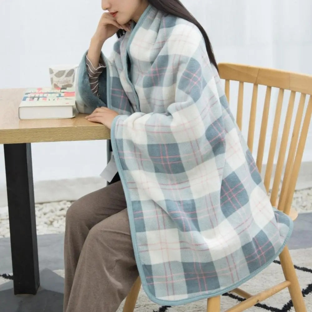 Femme assise portant une cape poncho carreaux bleu gris avec boutons pression