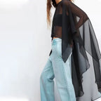 Cape poncho voile noir transparent femme porté avec jean clair, vue de profil