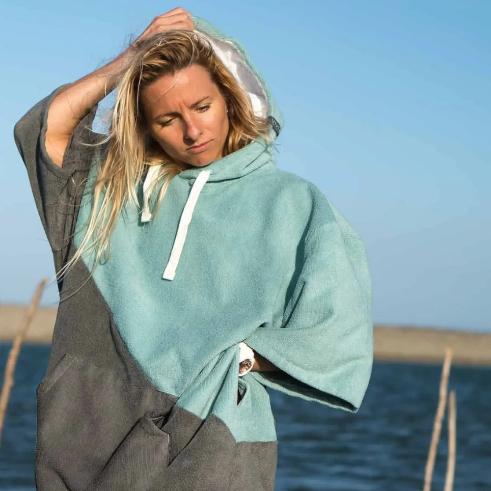 Femme portant poncho de bain microfibre bicolore vert gris avec capuche à la plage