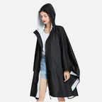 Femme portant un poncho pluie noir avec capuche et boutons pression, vue de face