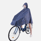 Femme à vélo portant poncho pluie bleu marine à capuche et bandes réfléchissantes