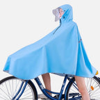 Femme portant poncho pluie bleu vélo avec capuche et visière sur bicyclette