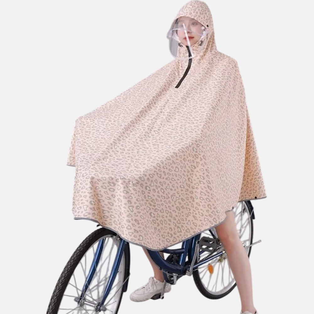 Femme à vélo portant un poncho pluie léopard beige avec capuche et visière transparente