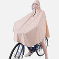 Femme à vélo portant un poncho pluie léopard beige avec capuche et visière transparente