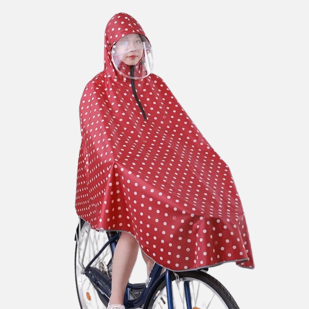 Enfant portant poncho pluie rouge à pois blancs avec capuche et visière sur vélo