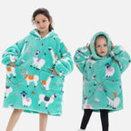 Deux enfants portent un poncho polaire turquoise à capuche avec motif lama coloré et poches