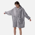 Femme portant un poncho polaire gris avec capuche et poches, manches longues