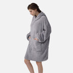 Femme portant un poncho polaire gris avec capuche et manches longues, mains dans les poches