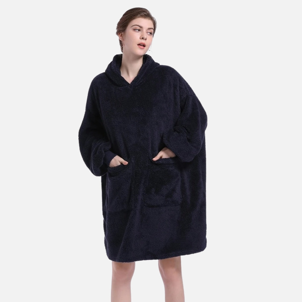 Femme portant un poncho polaire noir avec capuche et manches longues, poches visibles