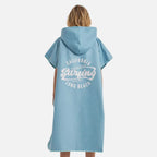 Femme portant poncho surf microfibre bleu avec capuche et motif surfing Long Beach