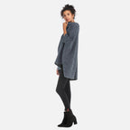 Femme portant un pull poncho gris chiné col roulé avec leggings noirs et boots