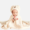 Bébé enveloppé dans serviette poncho microfibre écrue avec capuche lapin tenant jouet
